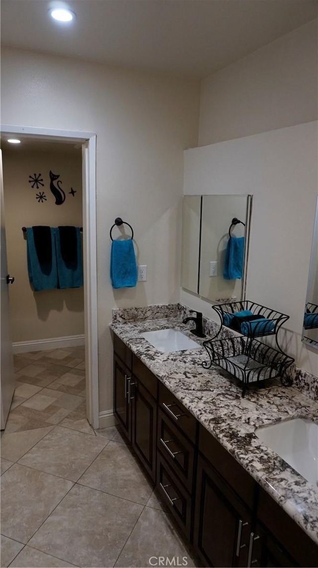 bathroom with a sink, baseboards, and double vanity