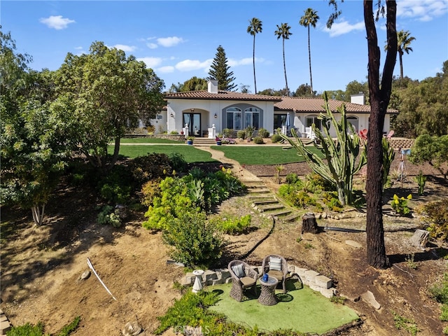 view of front facade with a front lawn, a chimney, a tile roof, and stucco siding