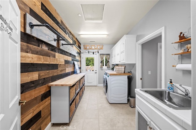 kitchen with light tile patterned floors, wood counters, white cabinetry, separate washer and dryer, and a sink