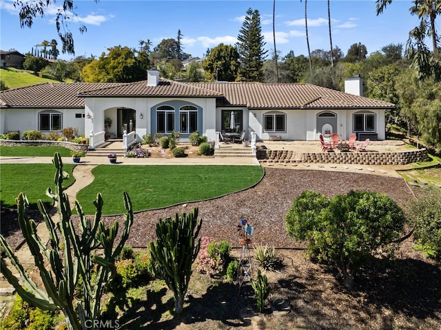 rear view of house featuring a chimney, a tile roof, and stucco siding