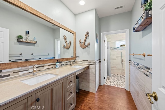 bathroom featuring a shower stall, a sink, visible vents, and tile walls