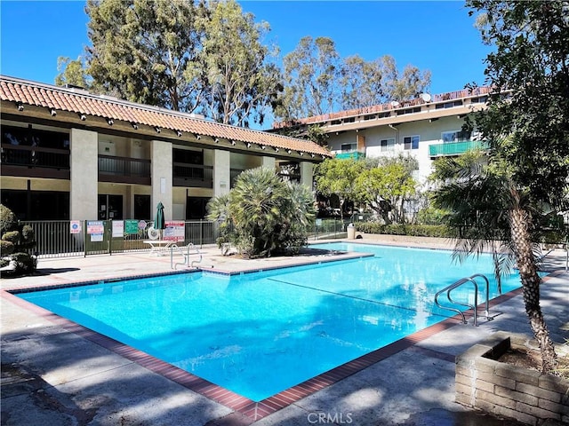 pool with a patio area and fence