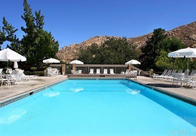 community pool featuring a patio area, fence, and a mountain view