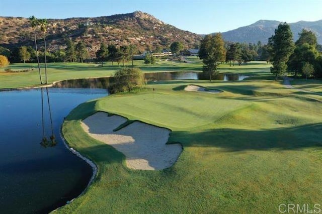 view of community with a yard, golf course view, and a water and mountain view