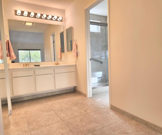 full bathroom featuring a wealth of natural light, a stall shower, baseboards, and double vanity