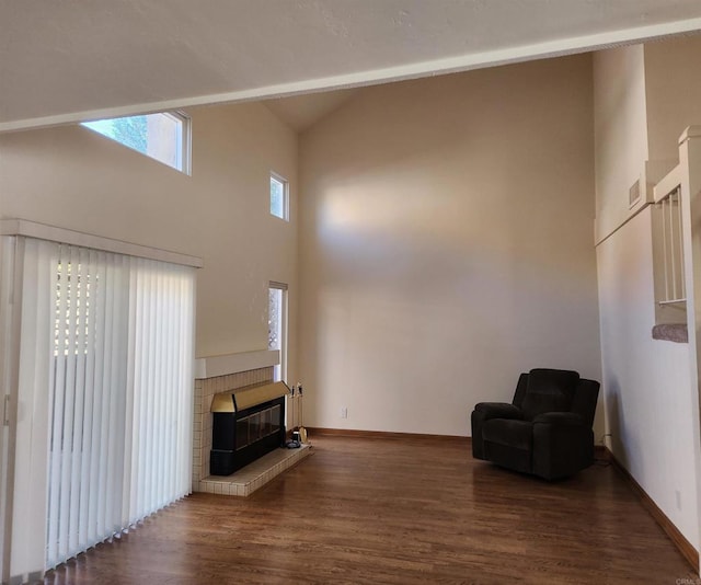 unfurnished room featuring high vaulted ceiling, a fireplace, baseboards, and wood finished floors