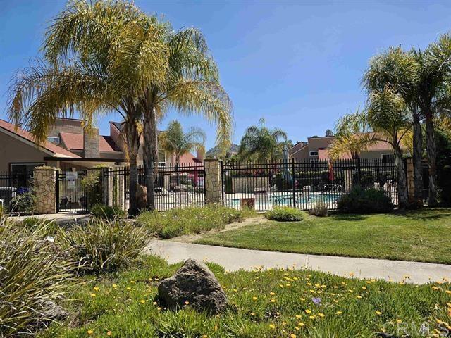 view of community with a yard, a swimming pool, and fence