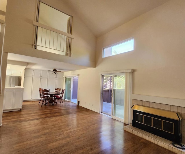 living room featuring ceiling fan, high vaulted ceiling, a fireplace, wood finished floors, and baseboards