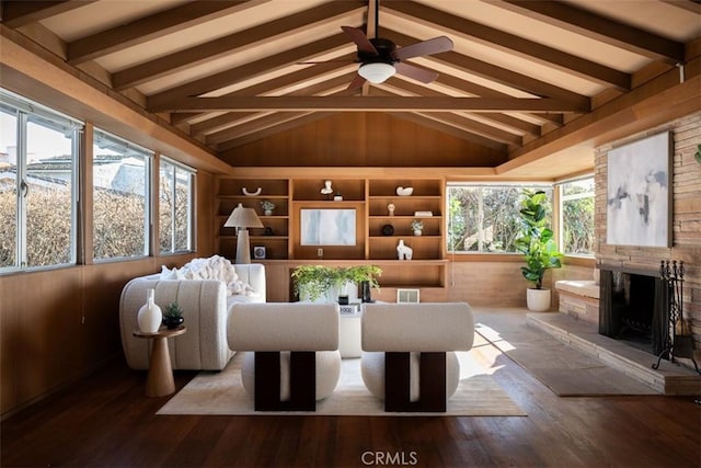 living area featuring vaulted ceiling with beams, ceiling fan, a fireplace, wood finished floors, and visible vents