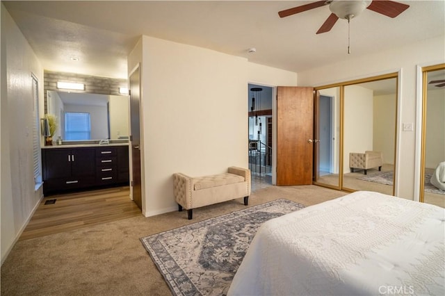 bedroom featuring light colored carpet, two closets, and a ceiling fan