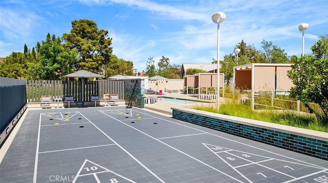 view of property's community with shuffleboard and fence