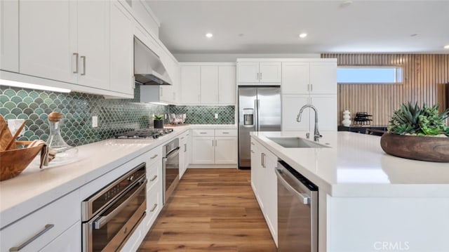 kitchen featuring white cabinets, appliances with stainless steel finishes, light countertops, under cabinet range hood, and a sink