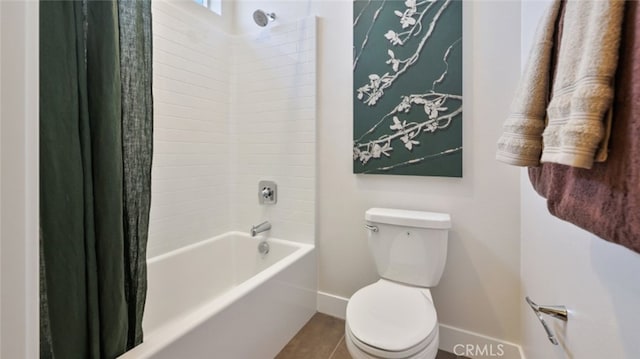 bathroom featuring toilet, baseboards, and shower / bath combo with shower curtain