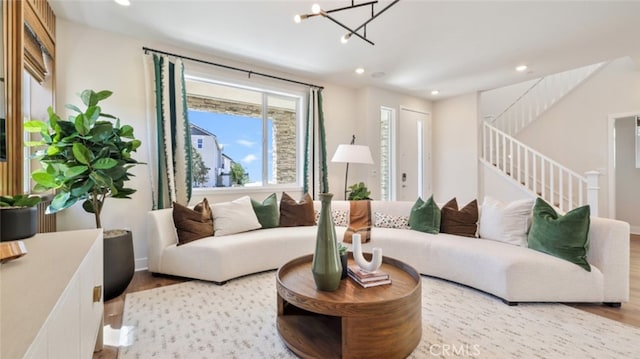 living area with an inviting chandelier, stairs, wood finished floors, and recessed lighting