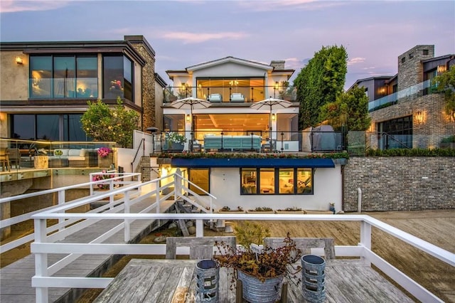 rear view of property with a balcony, stucco siding, stairs, and outdoor dining space