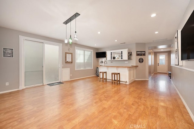 unfurnished living room with light wood-type flooring, baseboards, and recessed lighting