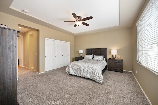 bedroom featuring carpet floors, baseboards, a tray ceiling, and a closet