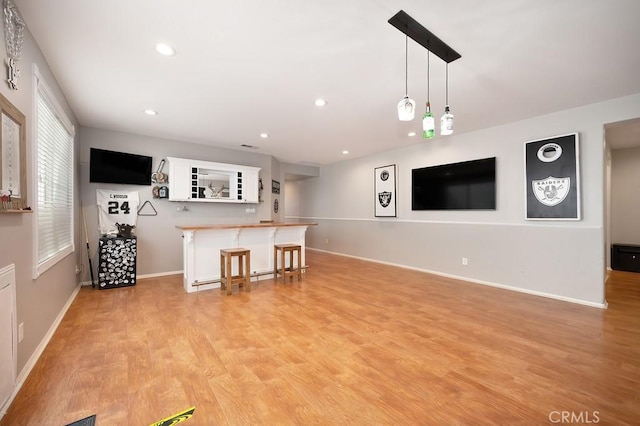 unfurnished living room with a dry bar, light wood-style flooring, baseboards, and recessed lighting