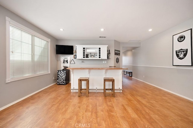 kitchen with a breakfast bar, white cabinetry, baseboards, open shelves, and light wood finished floors