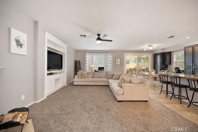 living room featuring visible vents, ceiling fan, and baseboards