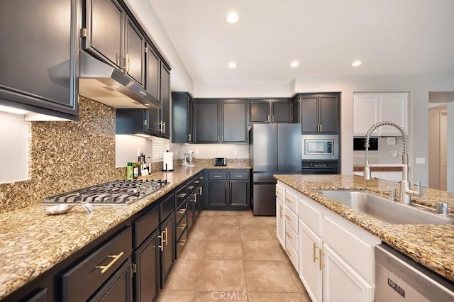 kitchen featuring tasteful backsplash, light stone countertops, stainless steel appliances, a sink, and recessed lighting