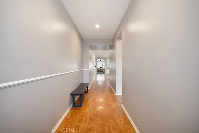 hall featuring light wood finished floors, recessed lighting, and baseboards