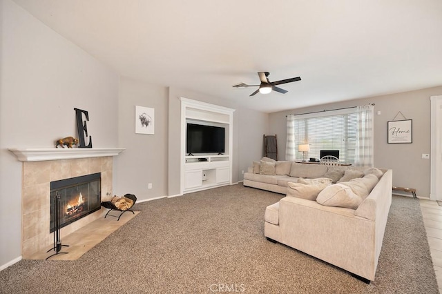 carpeted living room featuring ceiling fan, a fireplace, and baseboards