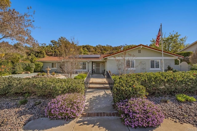 ranch-style house featuring stucco siding and roof mounted solar panels