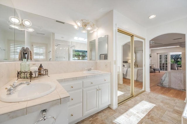 full bathroom with ensuite bathroom, a sink, visible vents, and a shower stall