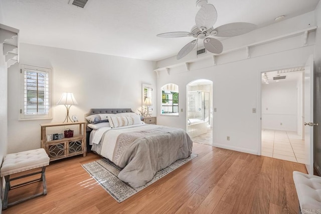 bedroom with visible vents, multiple windows, connected bathroom, and light wood-style flooring