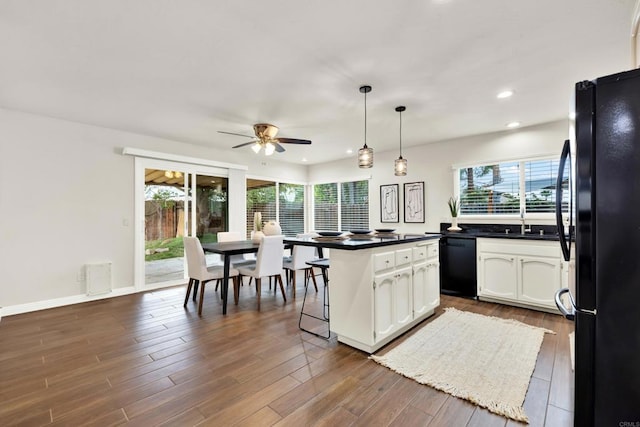 kitchen featuring black appliances, plenty of natural light, dark wood-style floors, and white cabinetry