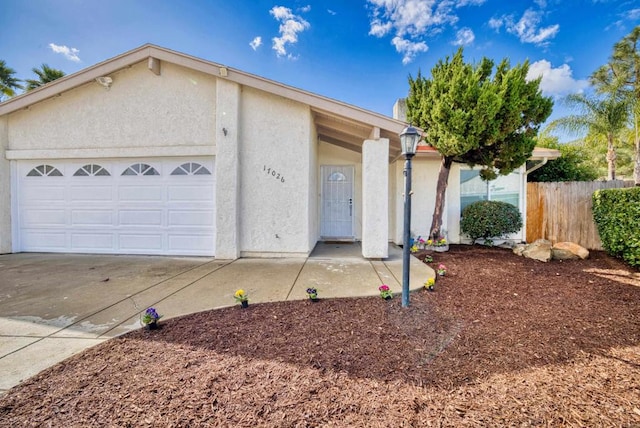 ranch-style home featuring concrete driveway, fence, an attached garage, and stucco siding