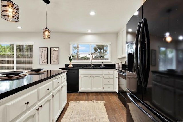 kitchen with dark wood-style flooring, dark countertops, white cabinets, a healthy amount of sunlight, and black appliances