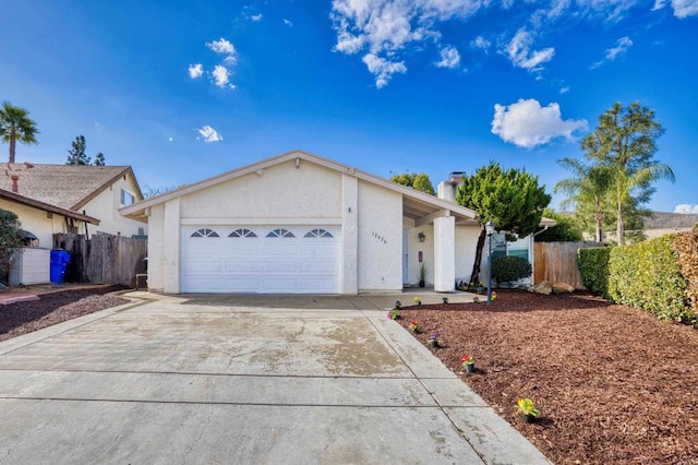 view of front of home featuring a chimney, stucco siding, concrete driveway, an attached garage, and fence