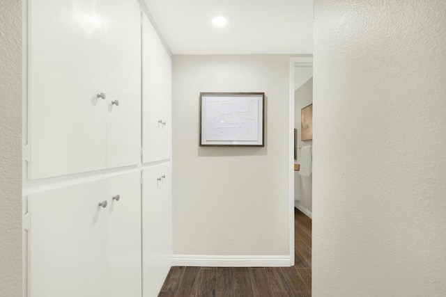 hallway featuring dark wood-style flooring and baseboards