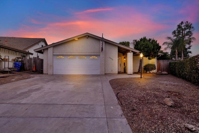 mid-century inspired home featuring a chimney, stucco siding, fence, a garage, and driveway