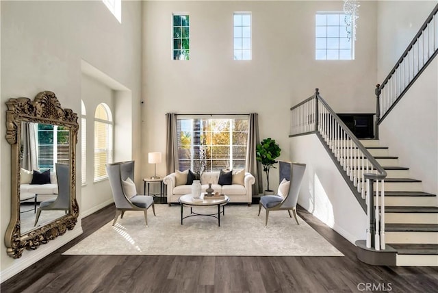 living area featuring stairway, baseboards, a healthy amount of sunlight, and wood finished floors