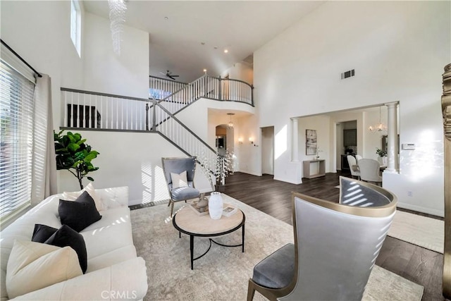 living room with stairway, wood finished floors, visible vents, a high ceiling, and a notable chandelier