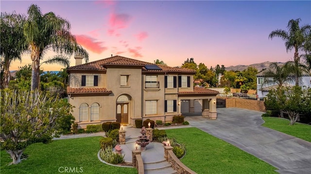 mediterranean / spanish house featuring roof mounted solar panels, a lawn, driveway, and stucco siding