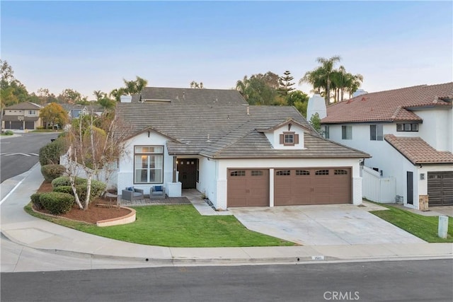 view of front of home with stucco siding, fence, a garage, driveway, and a front lawn