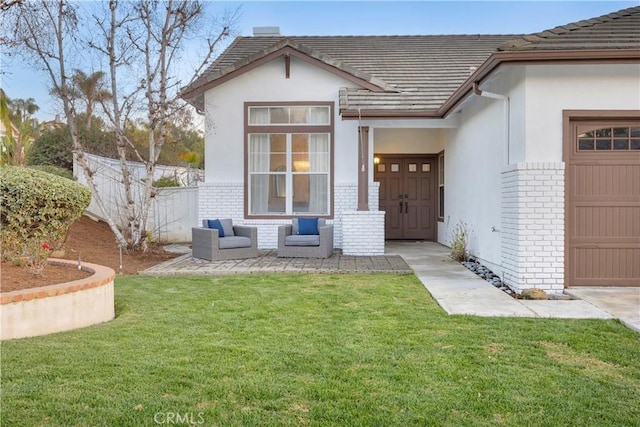 exterior space featuring brick siding, a yard, stucco siding, fence, and a garage