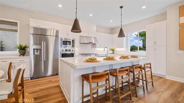 kitchen with appliances with stainless steel finishes, a sink, white cabinets, and under cabinet range hood