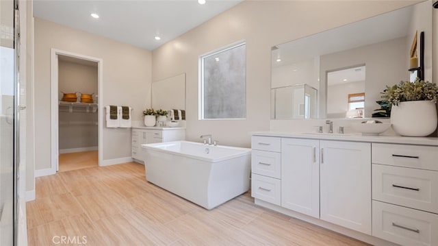 full bath featuring a freestanding tub, recessed lighting, vanity, a spacious closet, and a shower stall