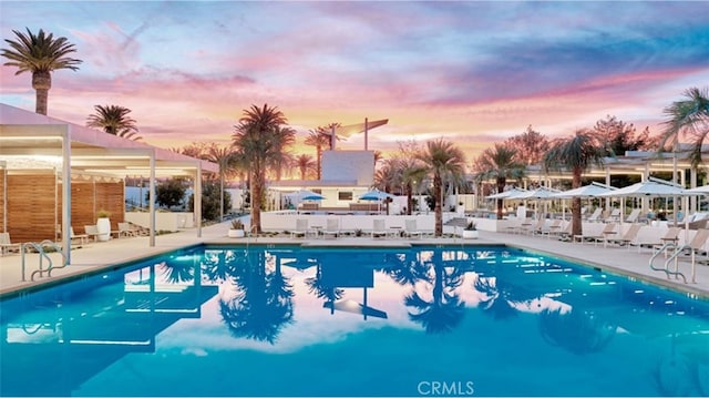 pool at dusk with a patio and a community pool