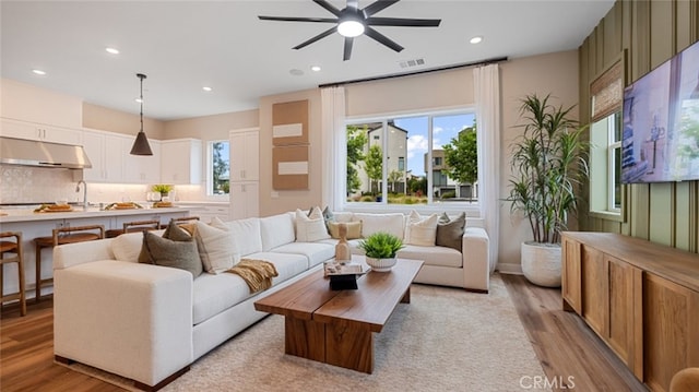 living area featuring light wood-type flooring, visible vents, and recessed lighting