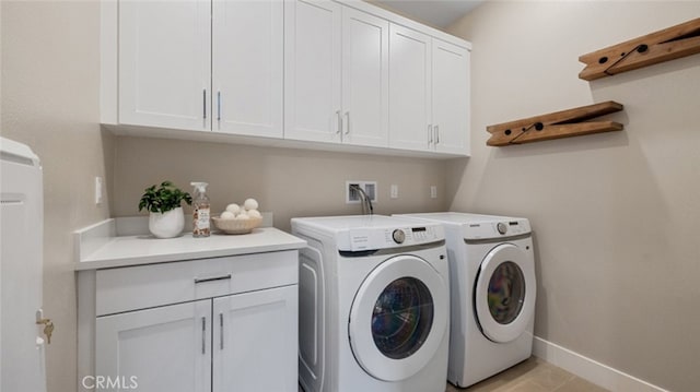 laundry room with cabinet space, baseboards, and washer and clothes dryer