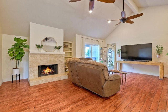 living room with ceiling fan, a premium fireplace, hardwood / wood-style flooring, and baseboards