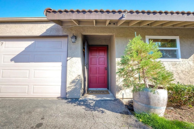 doorway to property featuring an attached garage and stucco siding