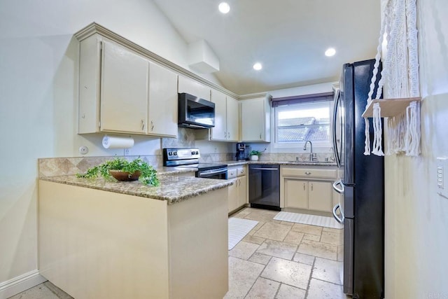 kitchen with appliances with stainless steel finishes, a peninsula, stone tile flooring, a sink, and recessed lighting