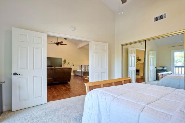 bedroom with ceiling fan, high vaulted ceiling, wood finished floors, visible vents, and a closet